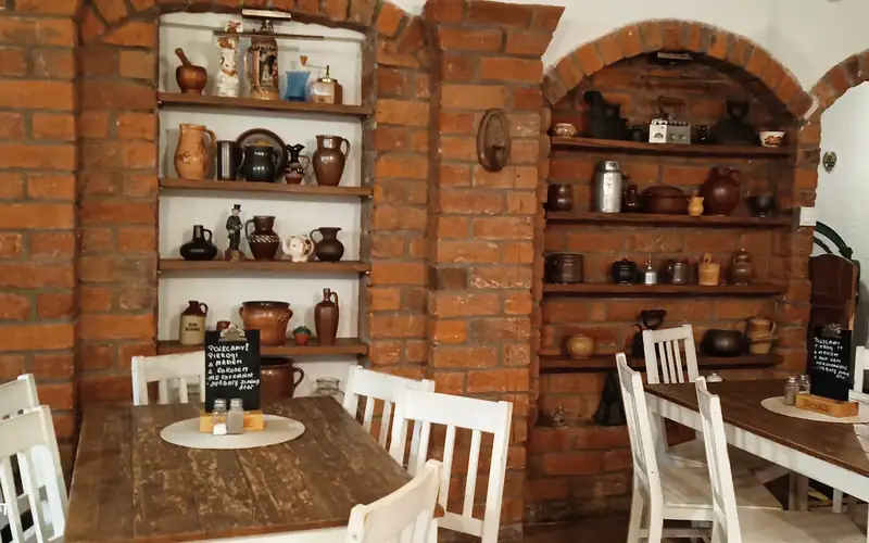 Sala z ceglanymi łukami i półkami z ceramiką